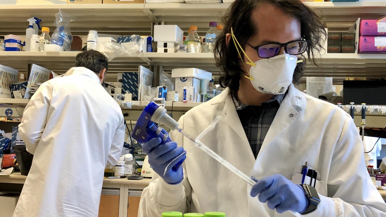 Ping Wee, un scientifique, travaille en laboratoire. Il porte un masque de protection.