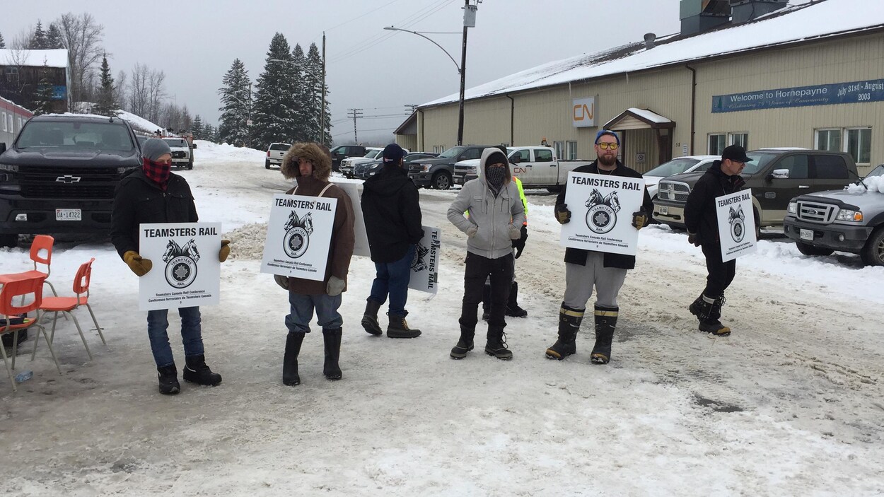 Des emplotés du CN tiennent des pancartes.