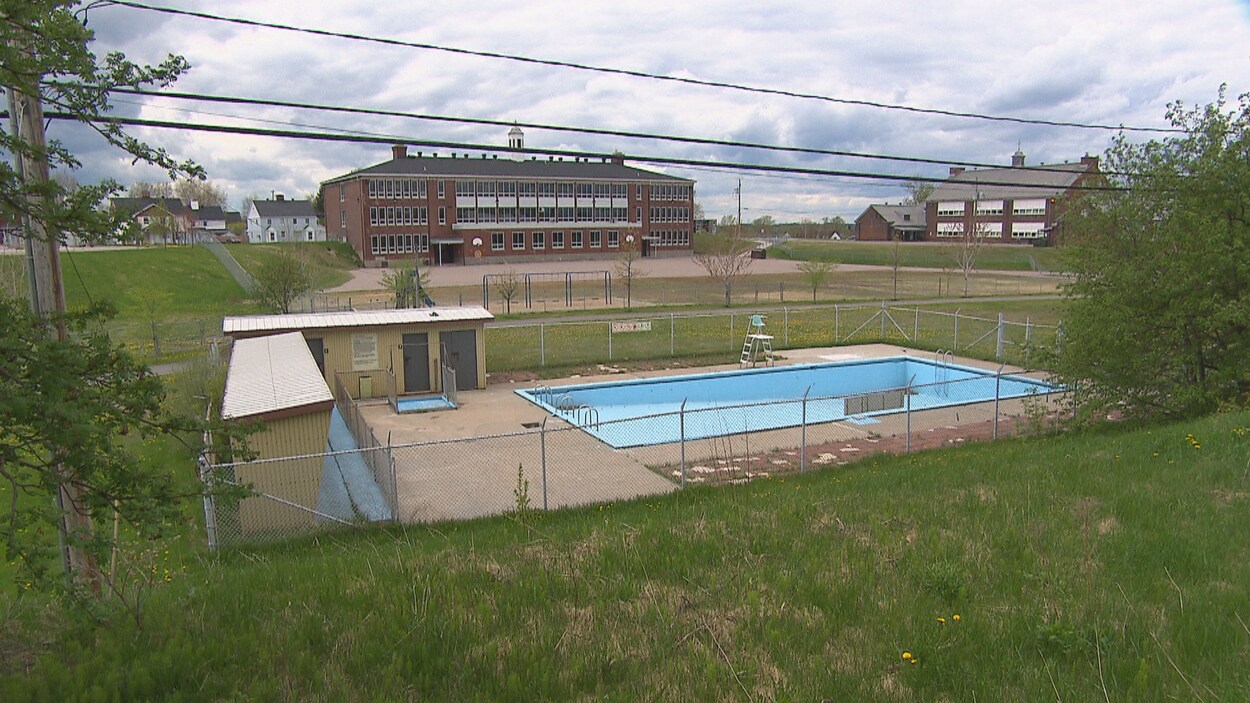 Une piscine vide se trouve à proximité de quelques bâtiments dans le secteur d'Arvida, à Saguenay.