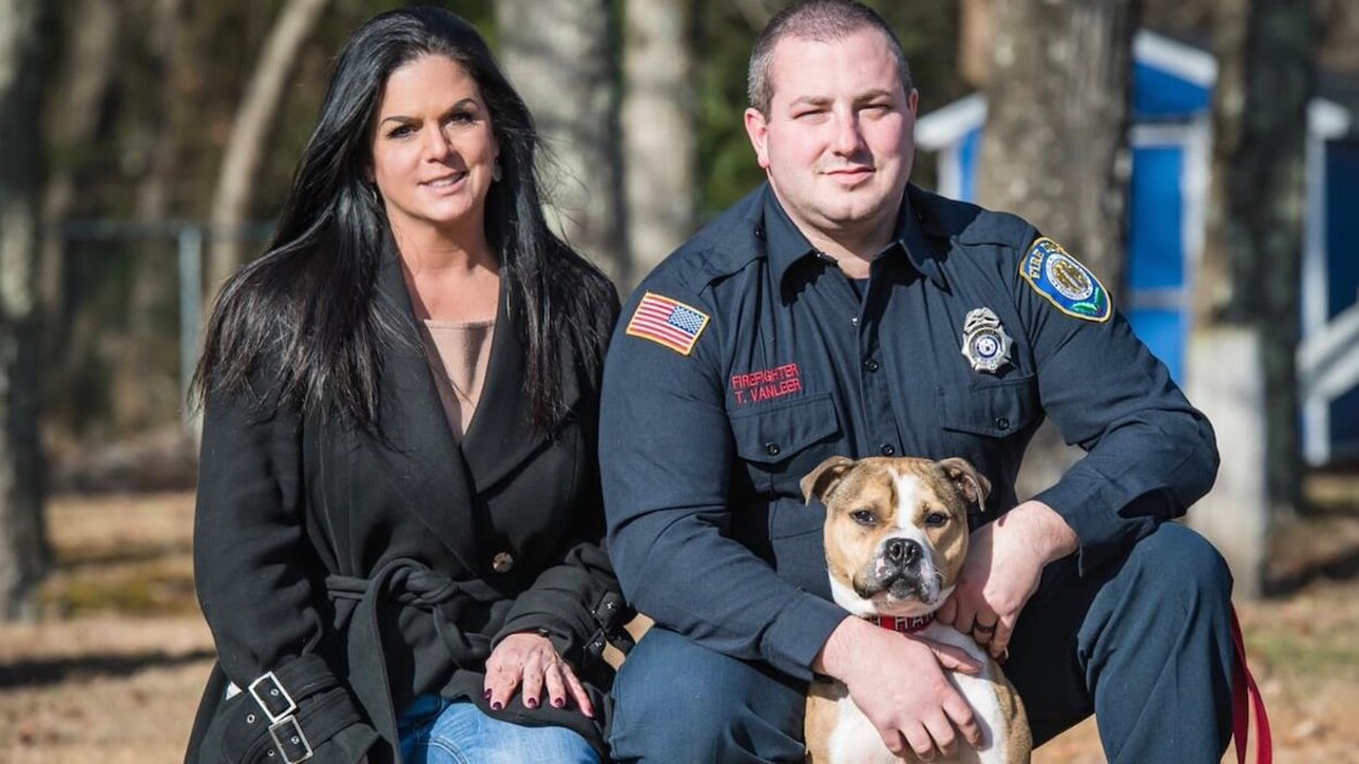 Une femme et un homme posent avec un chien en extérieur.