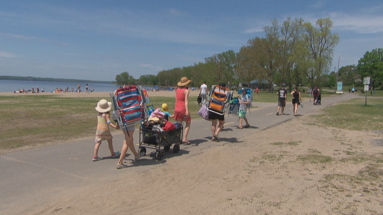 Des adultes et des enfants marchent sur une piste cyclable près de la plage du parc des Cèdres.