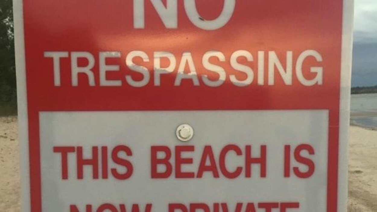 Un panneau rouge sur lequel il est indiqué « cette plage est désormais privée ».