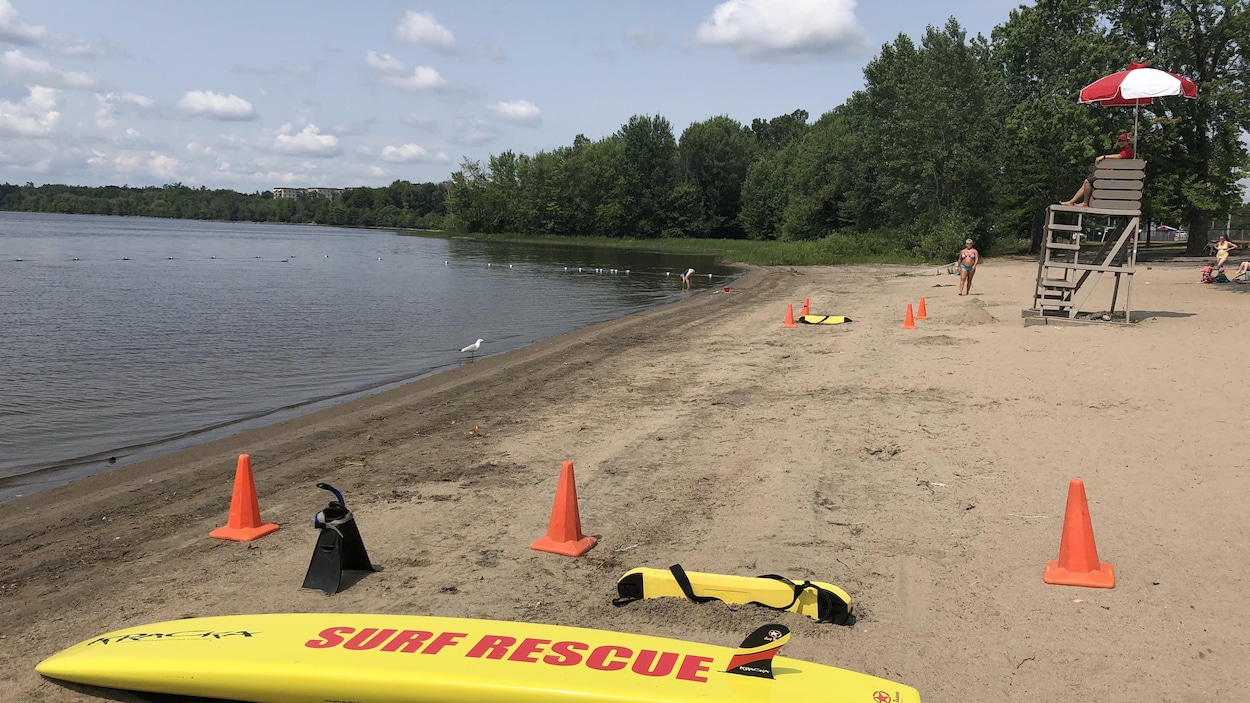 Une planche de surf destiné aux sauvetages aquatiques déposée sur l sable d'une plage à Gatineau Une planche de surf destiné aux sauvetages aquatiques déposée sur l sable d'une plage à Gatineau