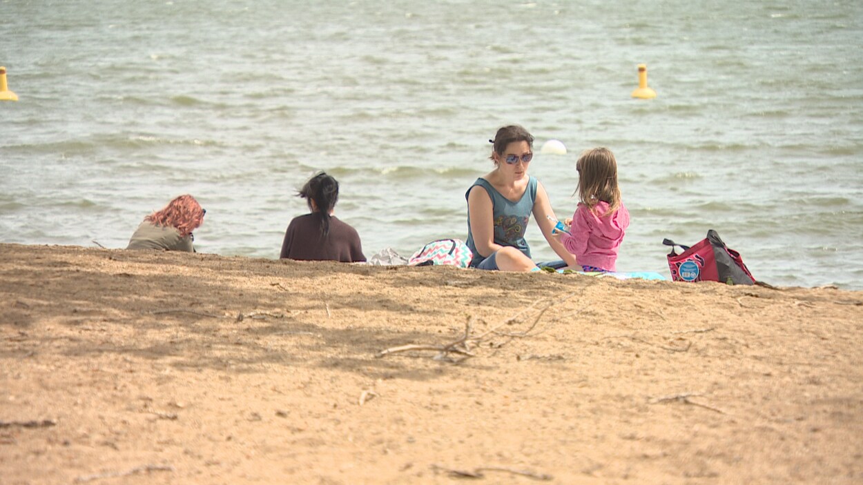 Des gens s'amusent sur une plage tout près de l'eau.