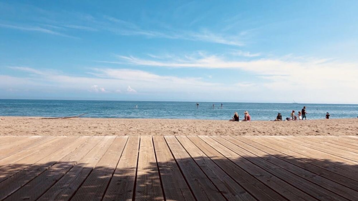 Une plage, avec quelques baigneurs et un soleil radieux.