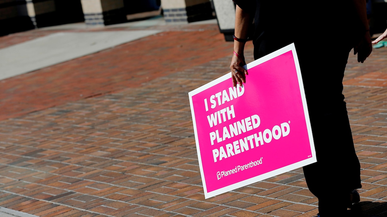 Une femme tient une pancarte indiquant : « Je soutiens Planned Parenthood », en référence aux cliniques de planification familiale qui sont dans le viseur de l'administration Trump.