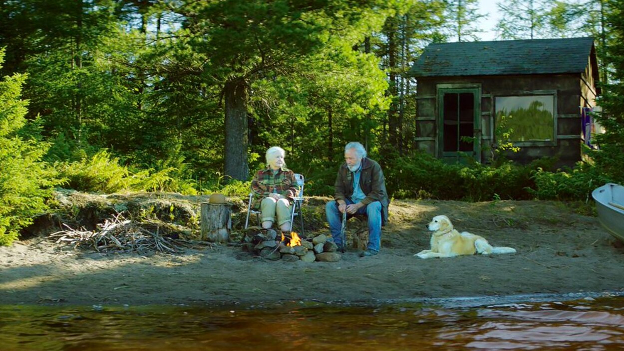 Un homme et une femme sur le bord d'une rivière avec un chien.