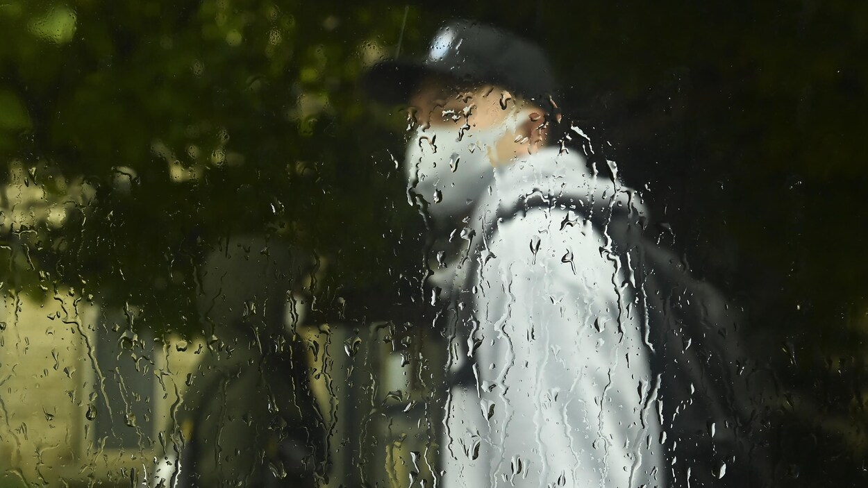 Un homme marche sous la pluie à Toronto.