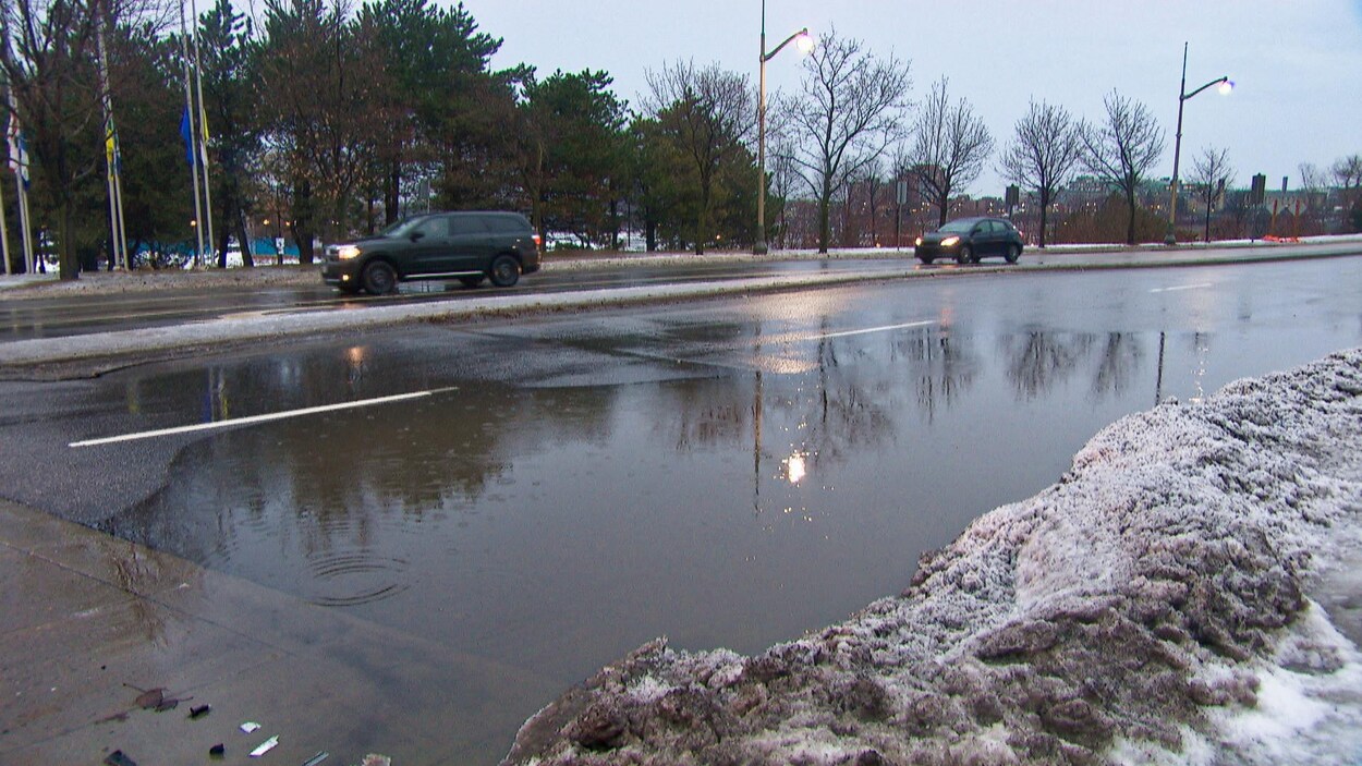 Une flaque d'eau occupe toute une voie d'une rue de Gatineau. Des voitures circulent dans les autres voies.