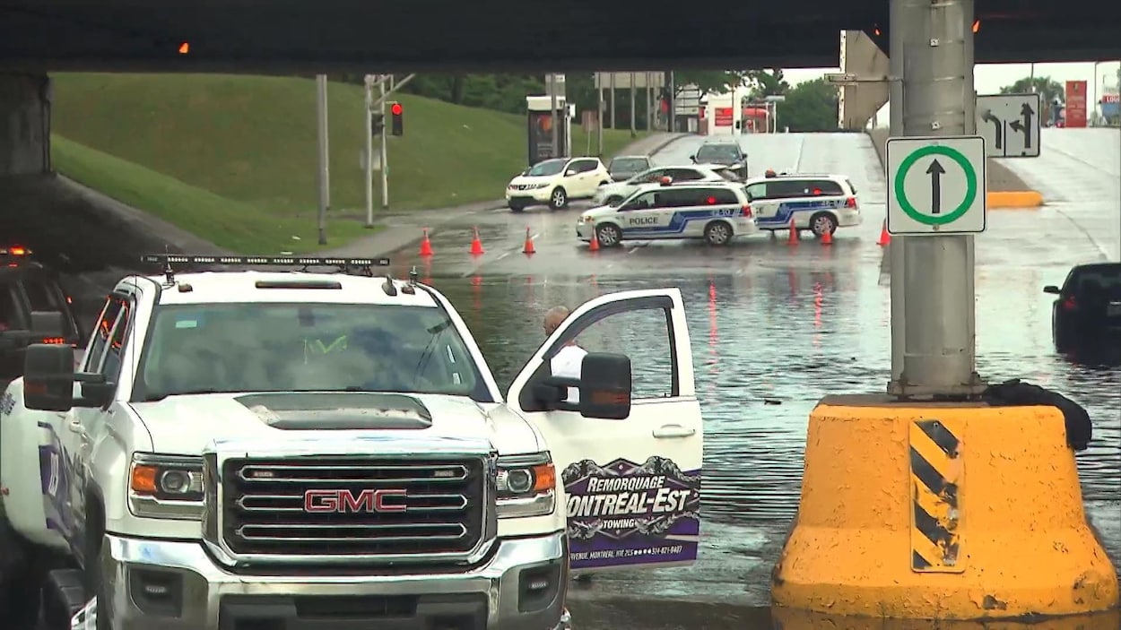 Des automobilistes sont coincés à la suite des pluies torrentielles survenues dans la matinée, à Montréal. Sur l'image sont représentées des étendues d'eau et des voitures à l'arrêt.