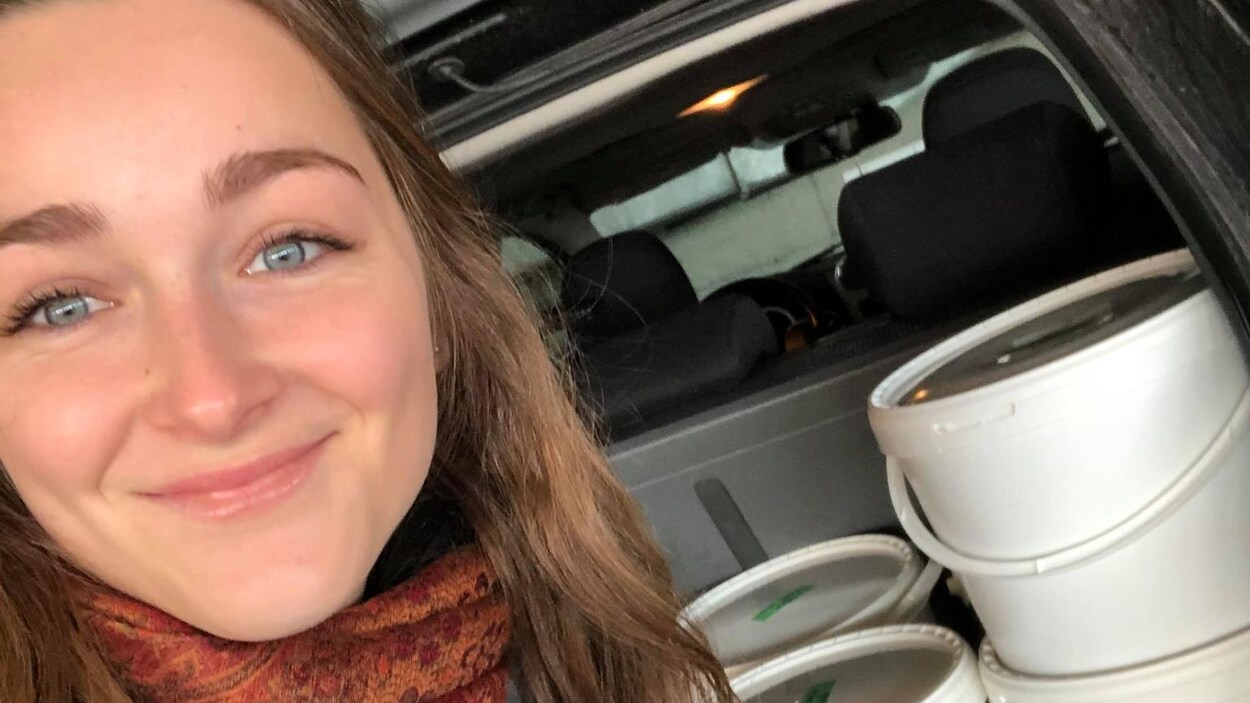 Un femme pose devant des repas à donner.