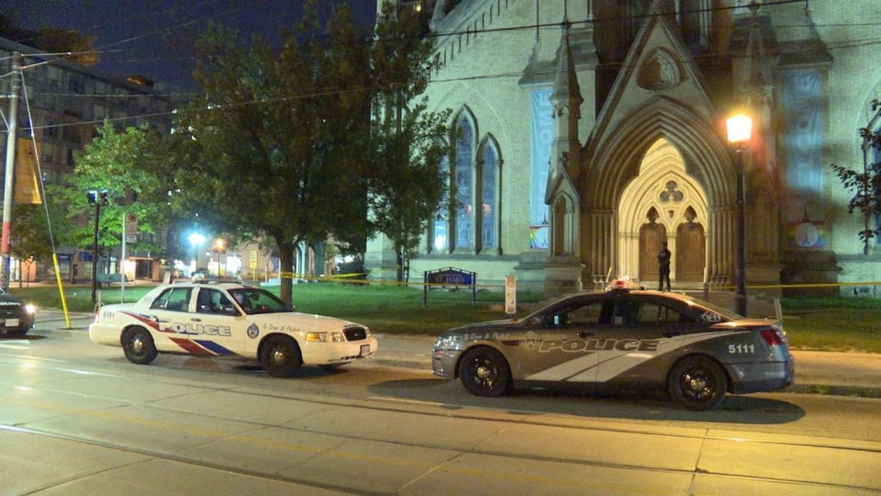 Deux voitures de police devant une cathédrale la nuit.