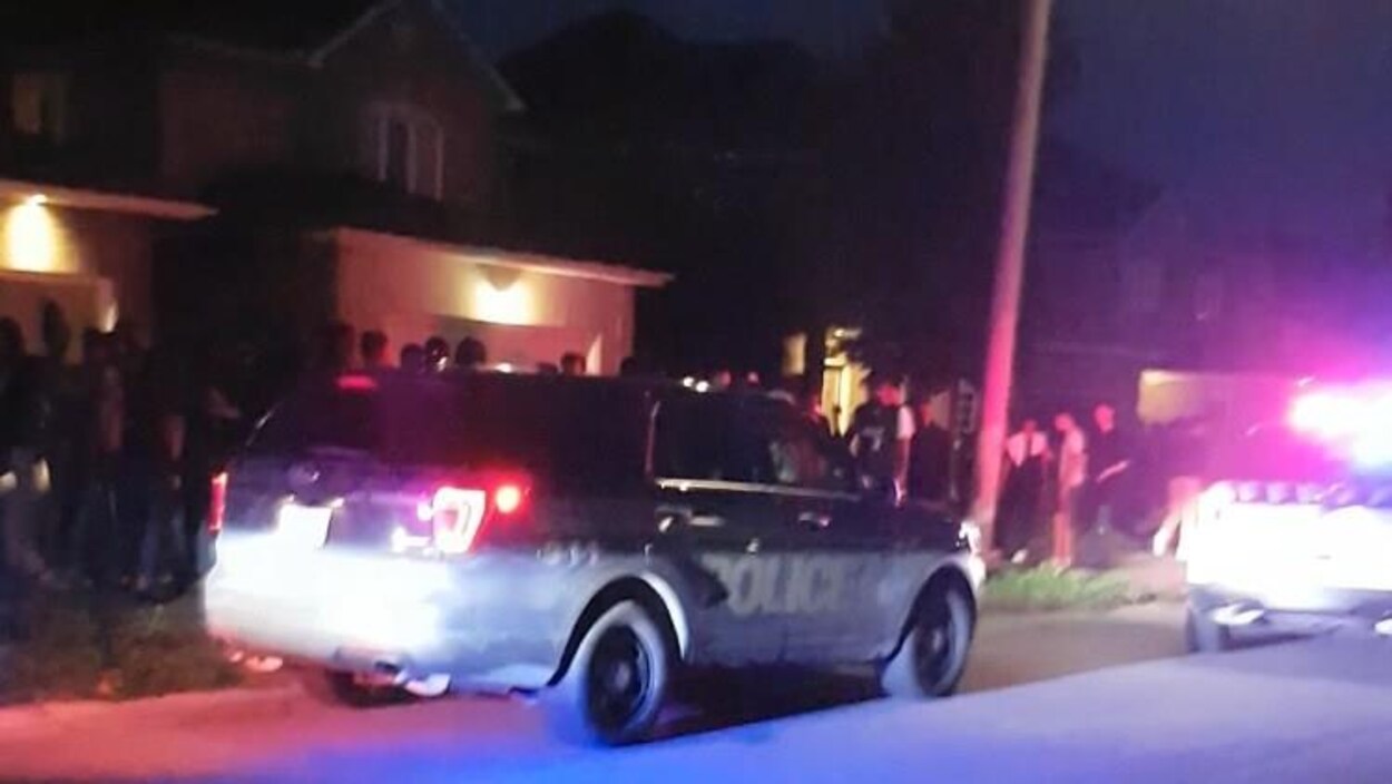 Des véhicules de police et des centaines d'adolescents devant une maison. Des véhicules de police et des centaines d'adolescents devant une maison.