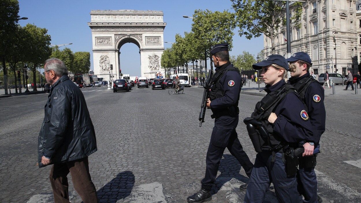Trois policiers français armés traversent les Champs-Élysées. Trois policiers français armés traversent les Champs-Élysées.