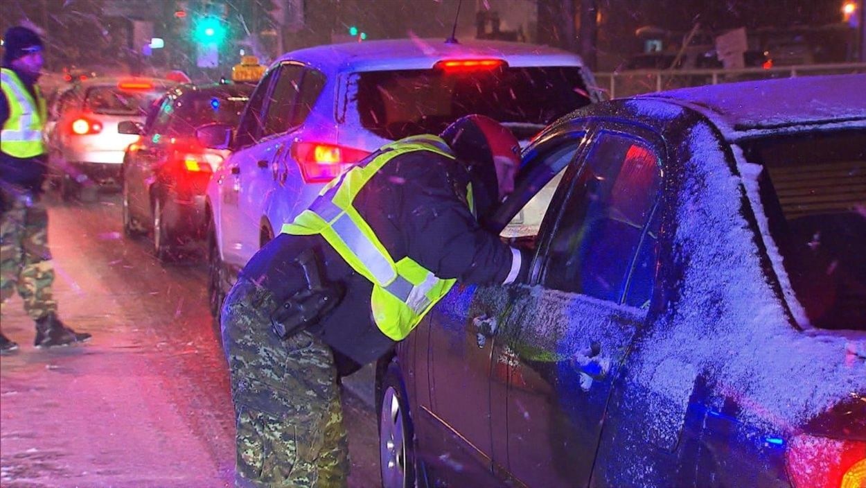 Un patrouilleur aborde un automobiliste immobilisé à un barrage routier