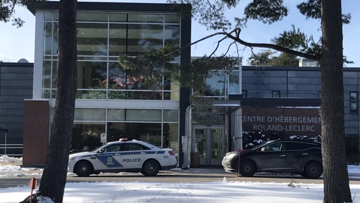 Une voiture de police devant un bâtiment avec l'inscription «Centre d'hébergement Roland-Leclerc».