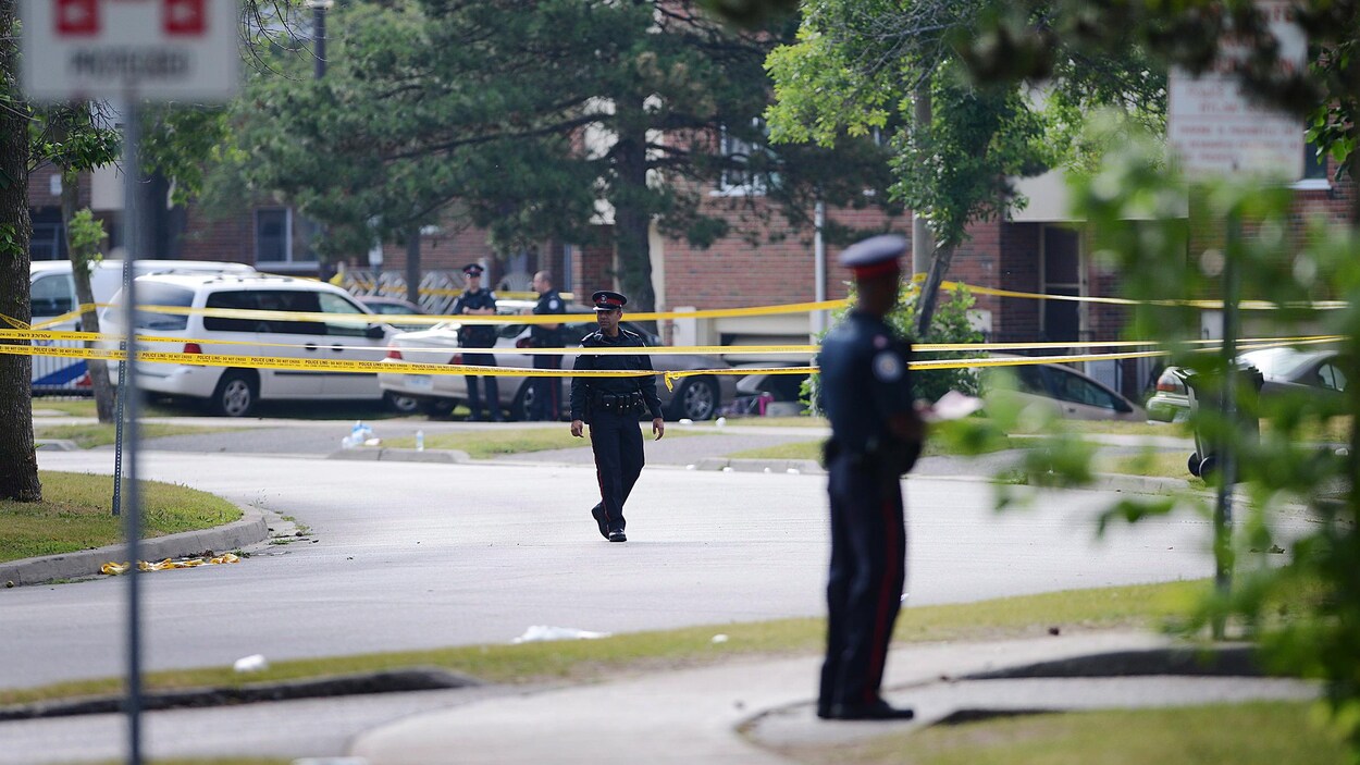 Photo de policiers qui montent la garde après la fusillade de la rue Danzig à Toronto en juillet 2012. Photo de policiers qui montent la garde après la fusillade de la rue Danzig à Toronto en juillet 2012.