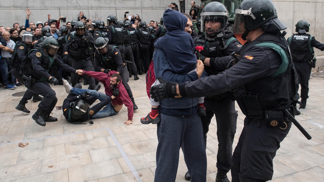 Deux policiers interviennent auprès d'un homme qui tient un enfant dans ses bras. En arrière-plan, trois policiers tentent de maîtriser un homme au sol. Deux policiers interviennent auprès d'un homme qui tient un enfant dans ses bras. En arrière-plan, trois policiers tentent de maîtriser un homme au sol.