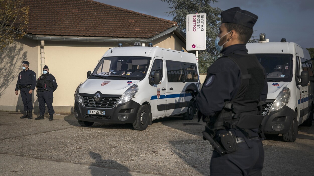 Les policiers montent la garde debout devant des camionnettes de police.
