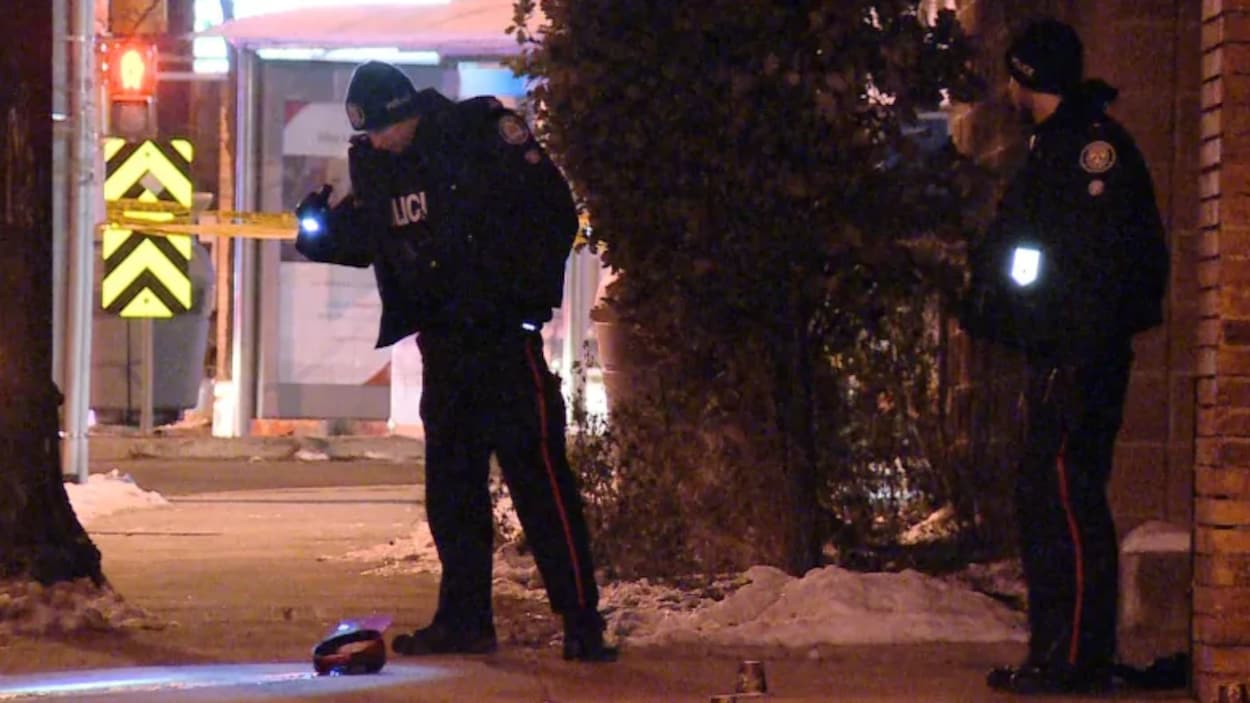 Des policiers regardent le sol avec la lumière de leur lampe torche.