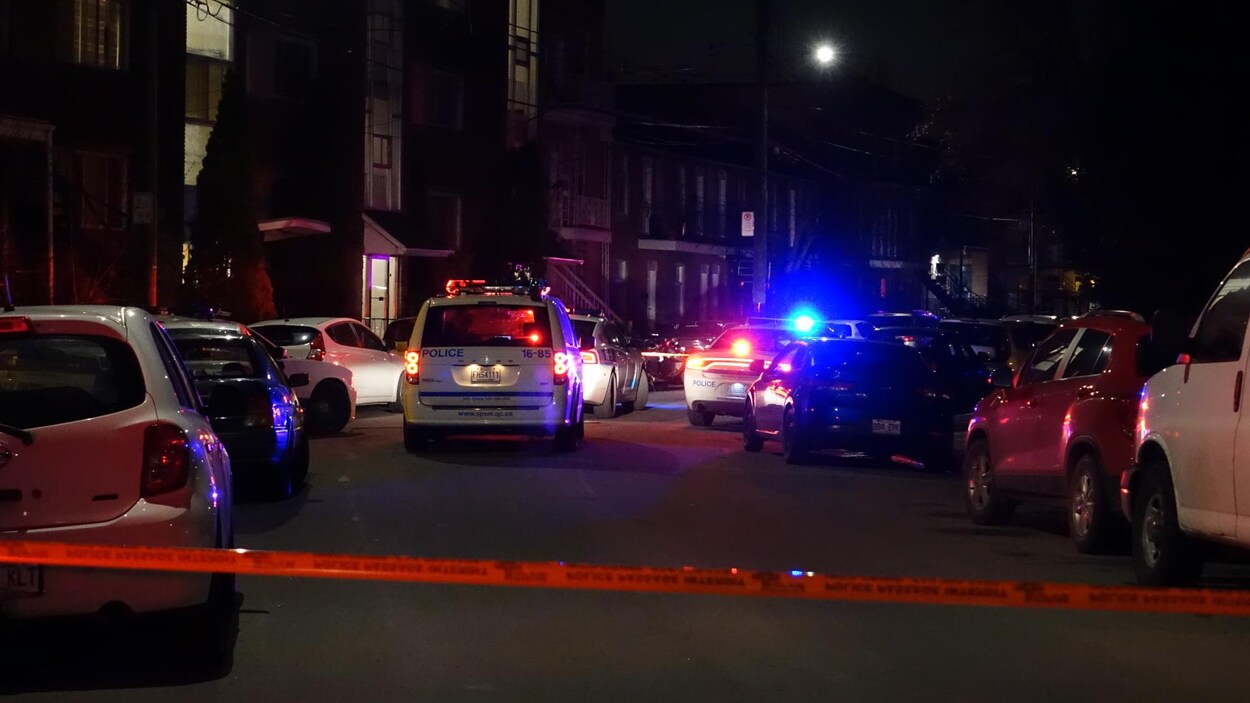 Cordon et véhicules de police devant des résidences.