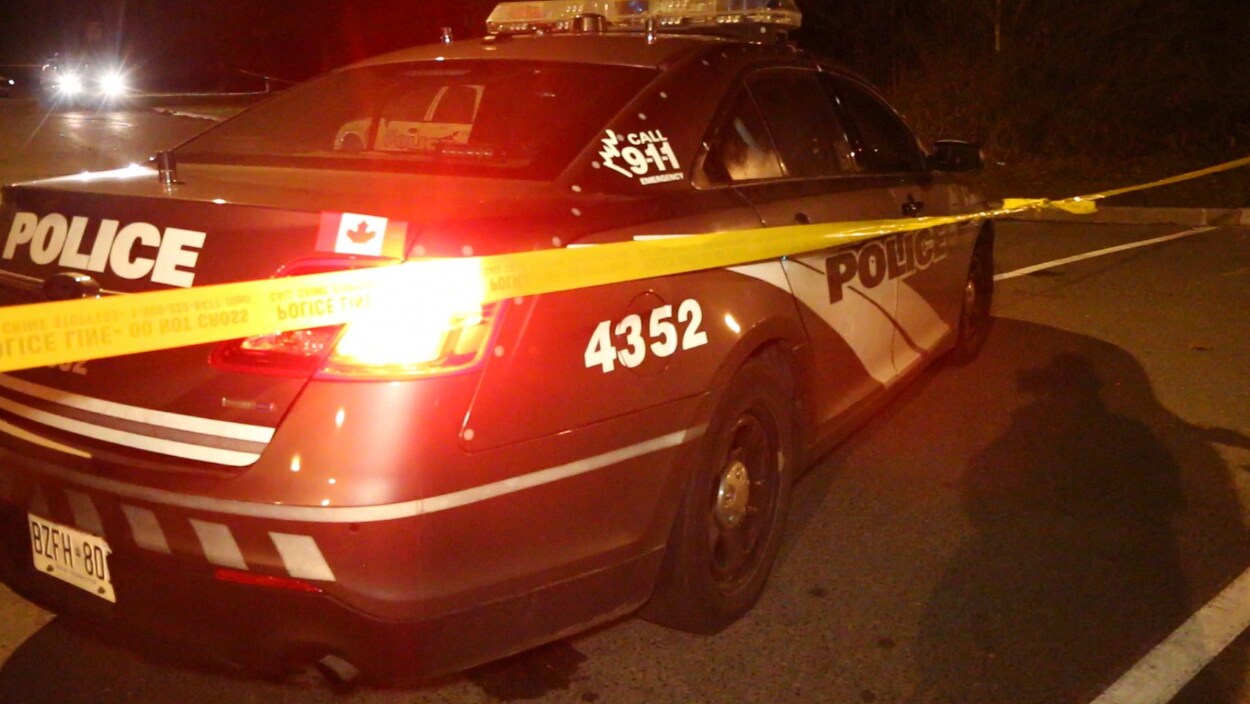 Photo d'une voiture de police et d'une bande jaune qui délimite le périmètre d'enquête. Photo d'une voiture de police et d'une bande jaune qui délimite le périmètre d'enquête.