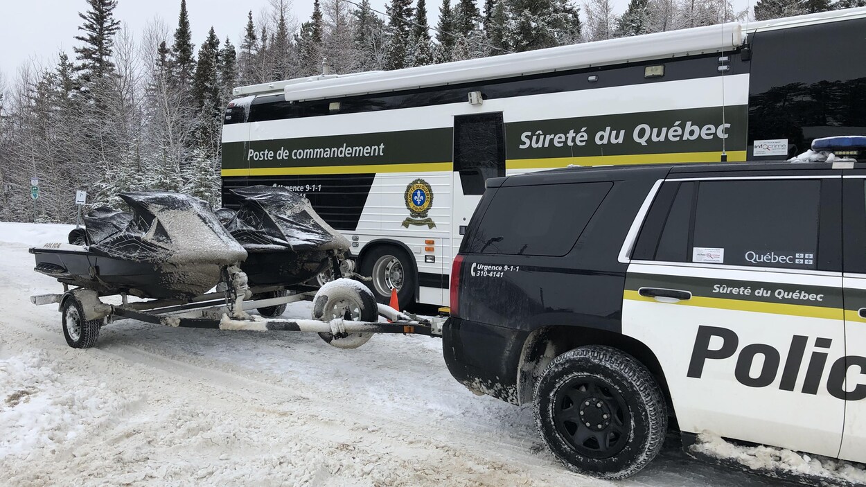 Deux motomarines installées sur une remorque derrière un véhicule de police.