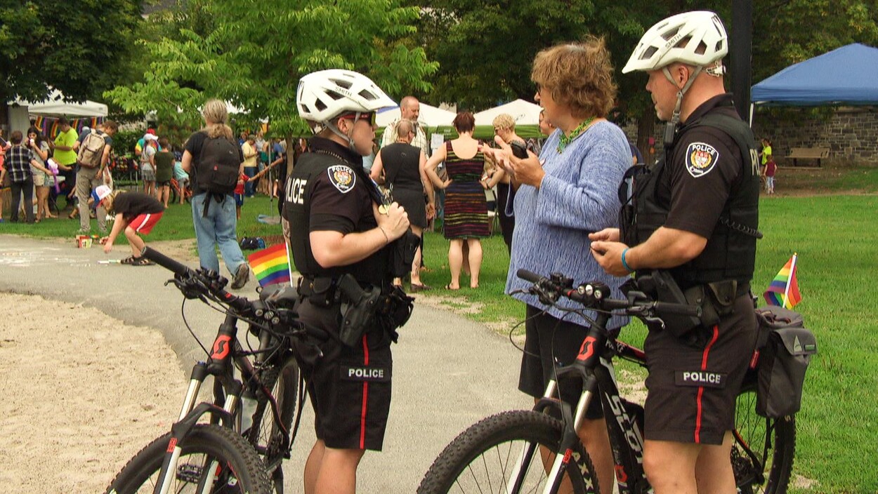 Des policiers à vélo avec un drapeau arc-en-ciel sur leur vélo