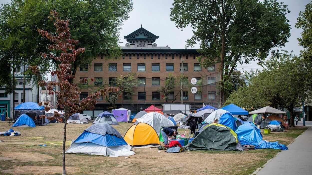 Des tentes dans un parc avec un édifice en arrière-plan.