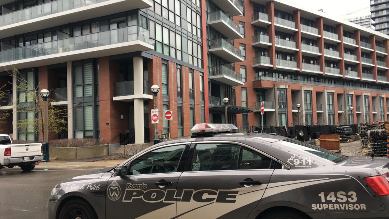 Photo d'une autopatrouille grise devant un immeuble en briques brunes.