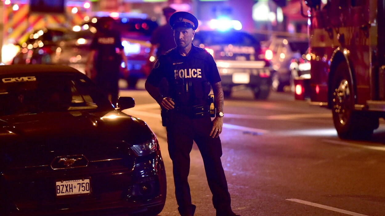Un policier se tient sur l'avenue Danforth, qui a été le théâtre d'une fusillade, à Toronto. Un policier se tient sur l'avenue Danforth, qui a été le théâtre d'une fusillade, à Toronto.