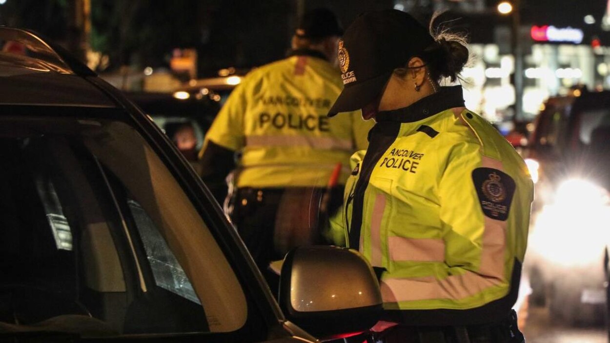 Une policière est debout à côté d'une voiture. Une policière est debout à côté d'une voiture.