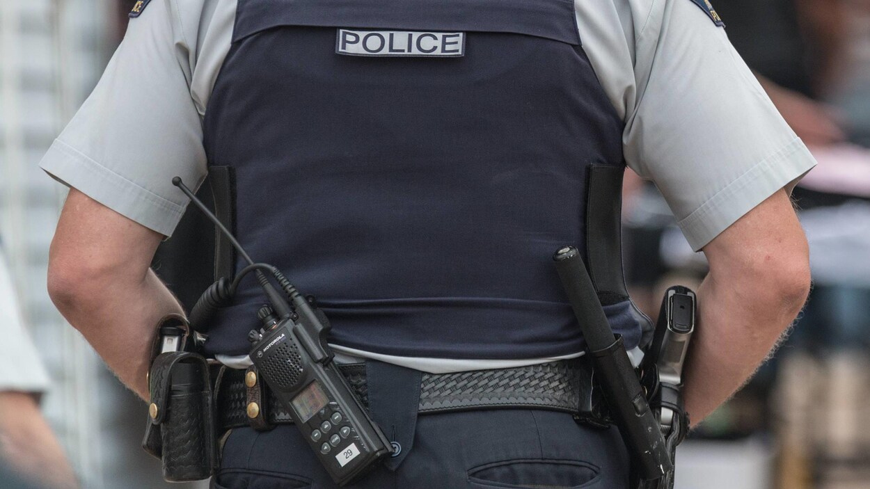 Gros plan sur la ceinture d'un policier et sur son arme de service.