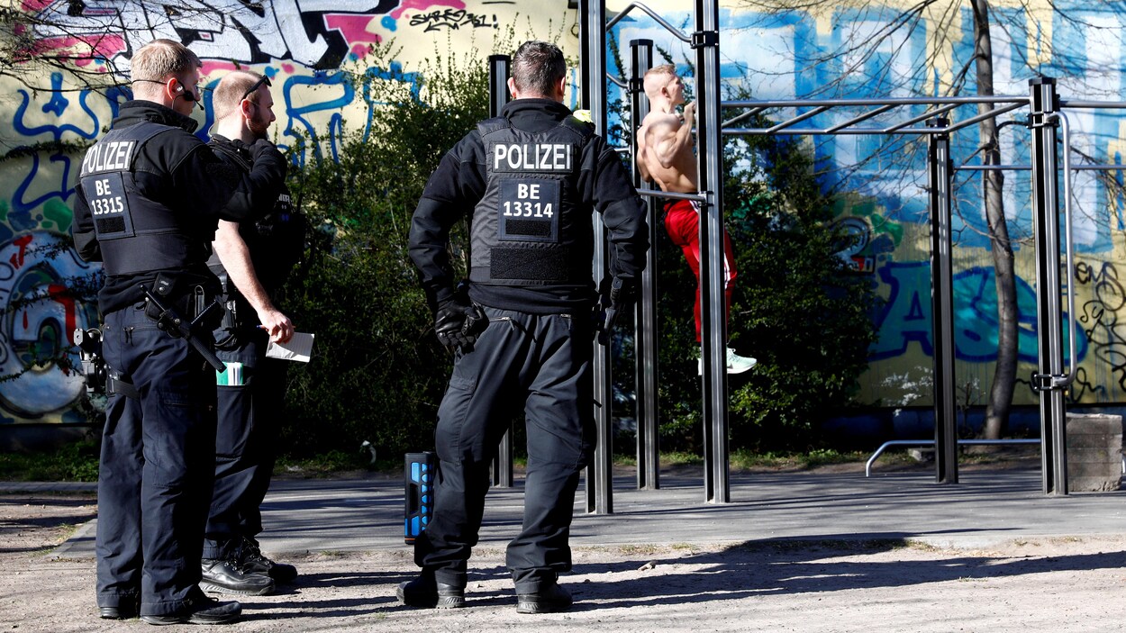 Trois policiers de dos regardent un homme faire de l'exercice.