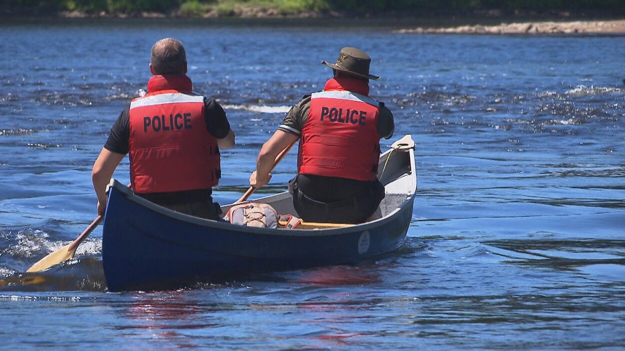 Deux policiers dans un canot sur une rivière.
