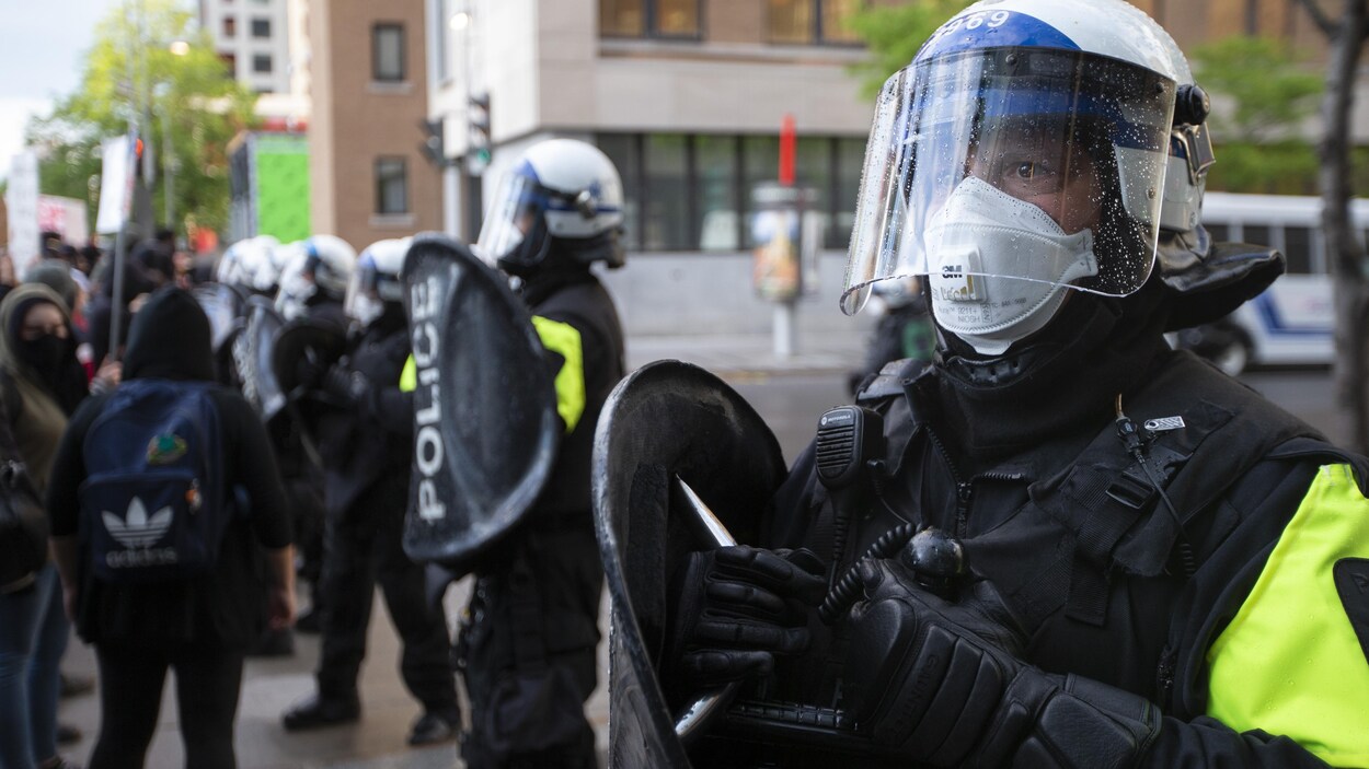 Des policiers avec leurs boucliers portant masque, casque et visière.
