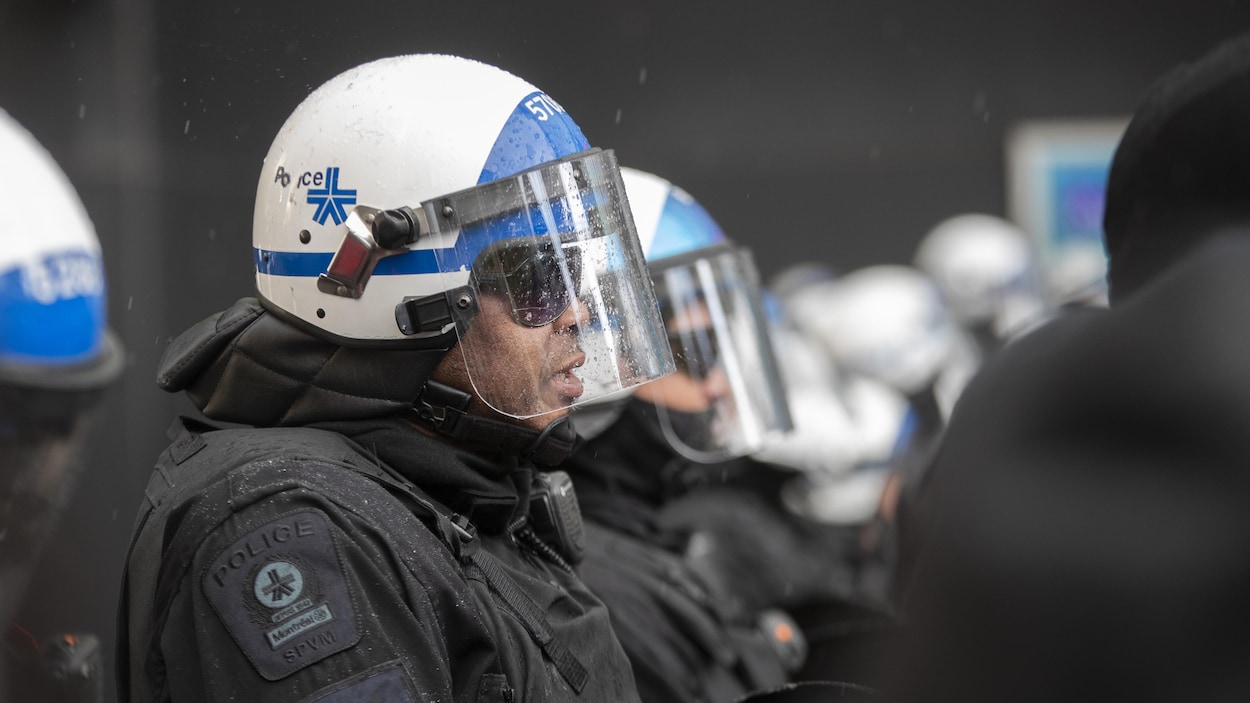 Des policiers côte à côte portant leur casque avec visière.