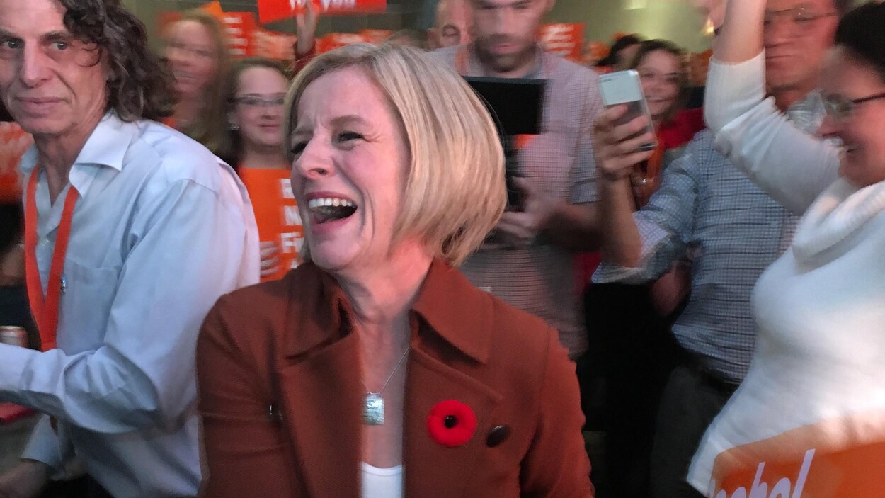 La chef du Nouveau Parti démocratique de l'Alberta Rachel Notley rit, au milieu d'un groupe de miltants.
