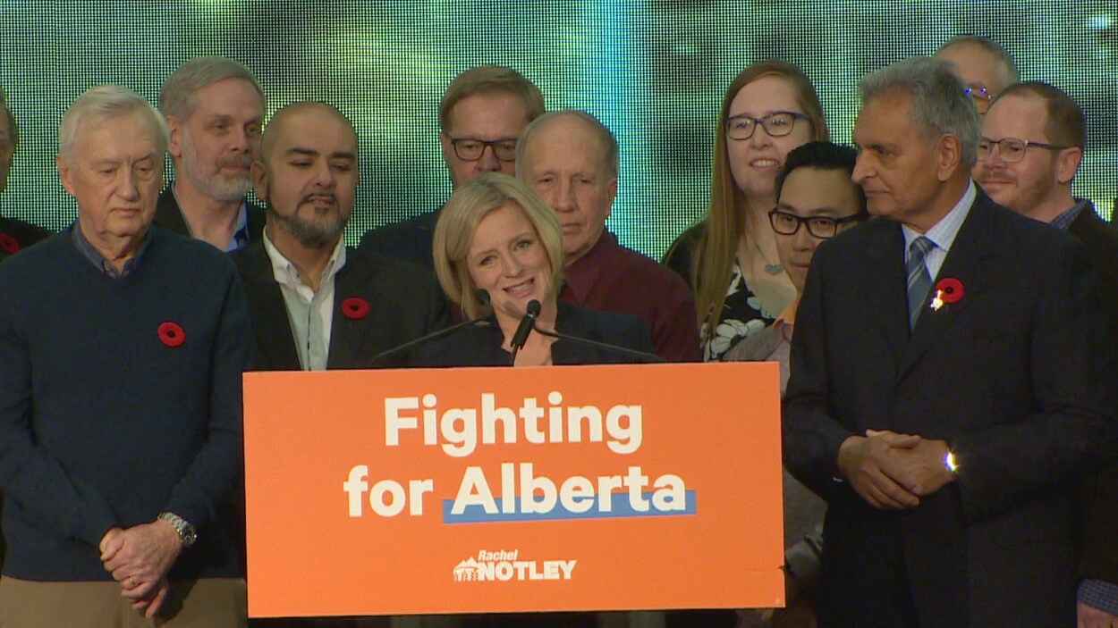 Rachel Notley s'exprime au podium, entourée des députés de son caucus.