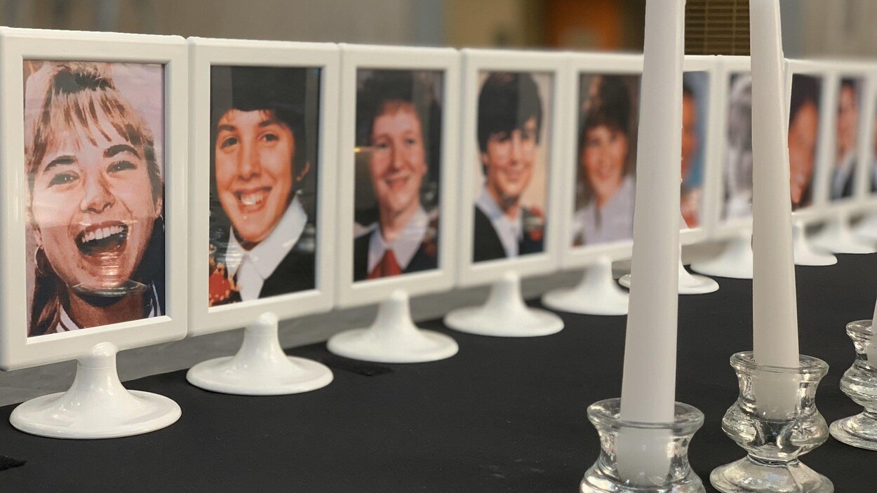 Les photos des 14 victimes de Polytechnique dans des cadres posés sur une table avec une rangée de chandelles blanches.