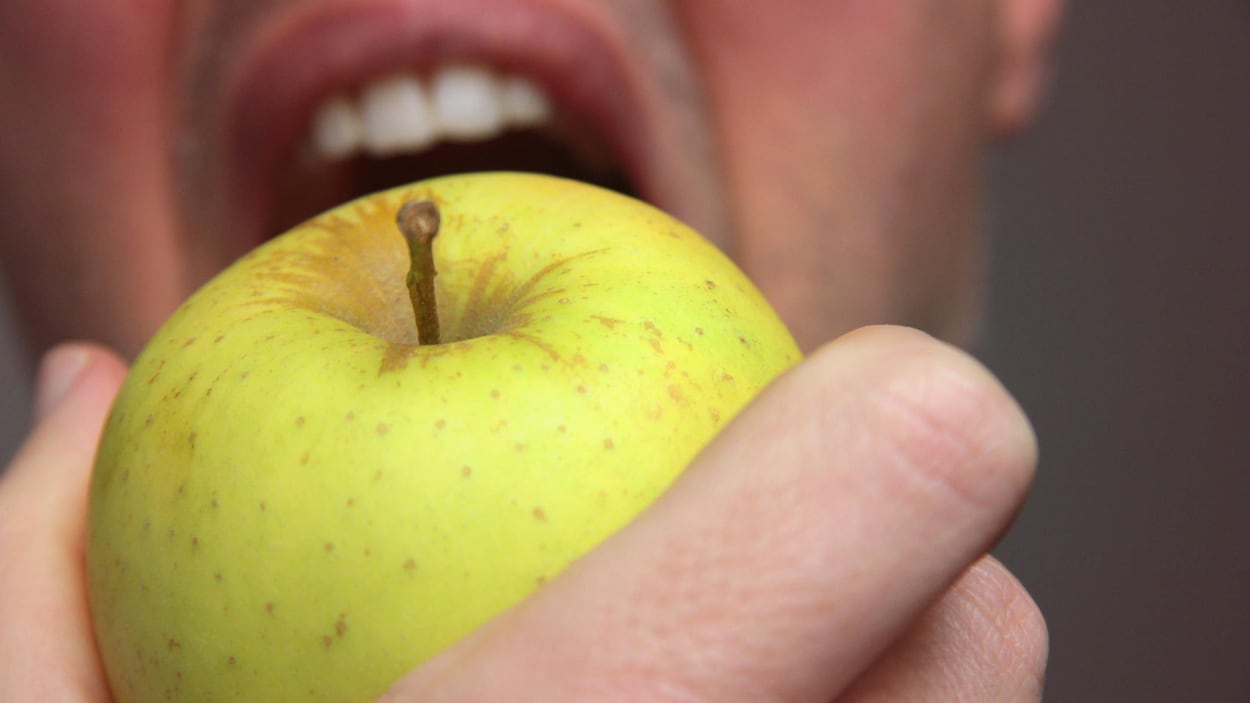 Un homme croque dans une pomme verte.