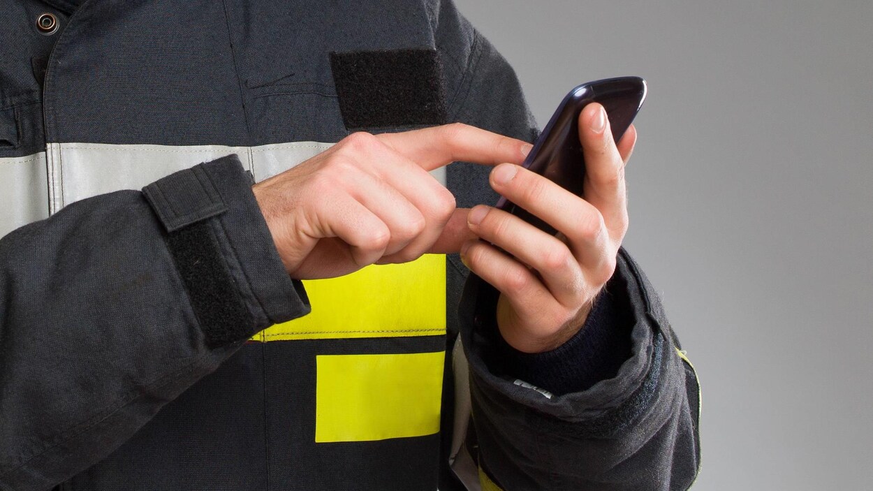 Un pompier utilise un téléphone cellulaire.