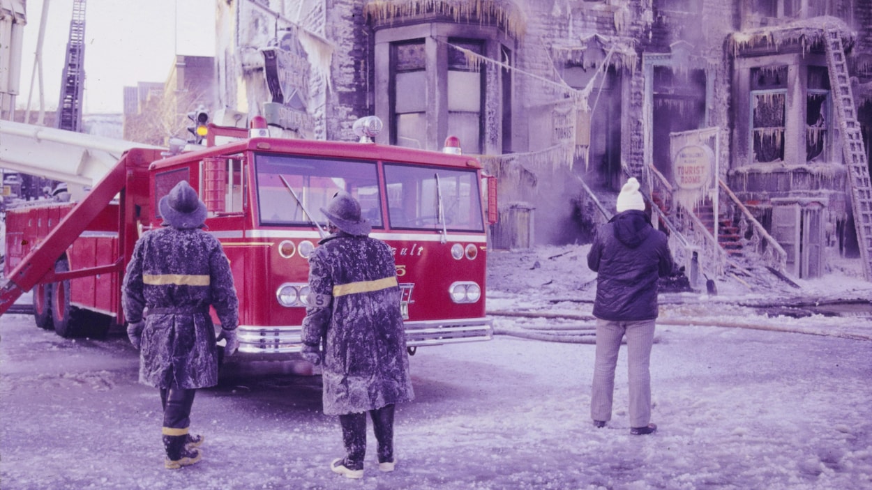 Pompiers montréalais près d'un camion suite à l'extinction d'un feu. Scène hivernale avec beaucoup de glace.