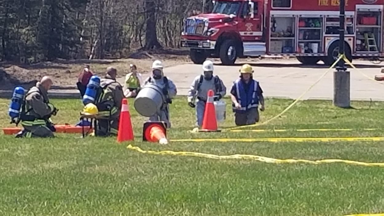Des pompiers dans le gazon entourés de cônes et devant un camion de pompiers. Des pompiers dans le gazon entourés de cônes et devant un camion de pompiers.