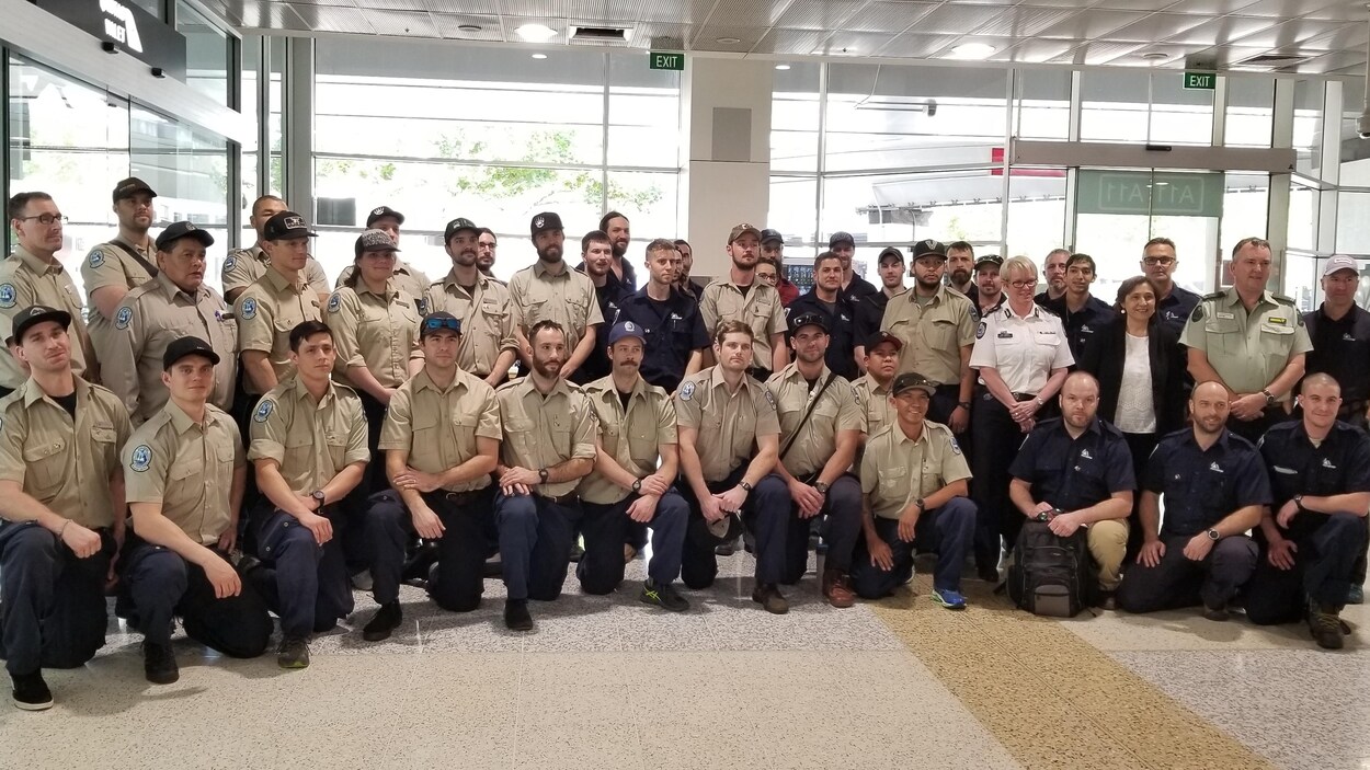 Le groupe de pompiers pose pour une photo à l'aéroport.