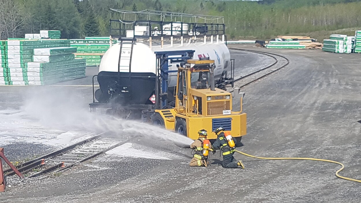 Deux pompiers sont accroupis sur le sol et tiennent un boyau d'arrosage dans leurs mains, d'où jaillit une mousse. Deux pompiers sont accroupis sur le sol et tiennent un boyau d'arrosage dans leurs mains, d'où jaillit une mousse.