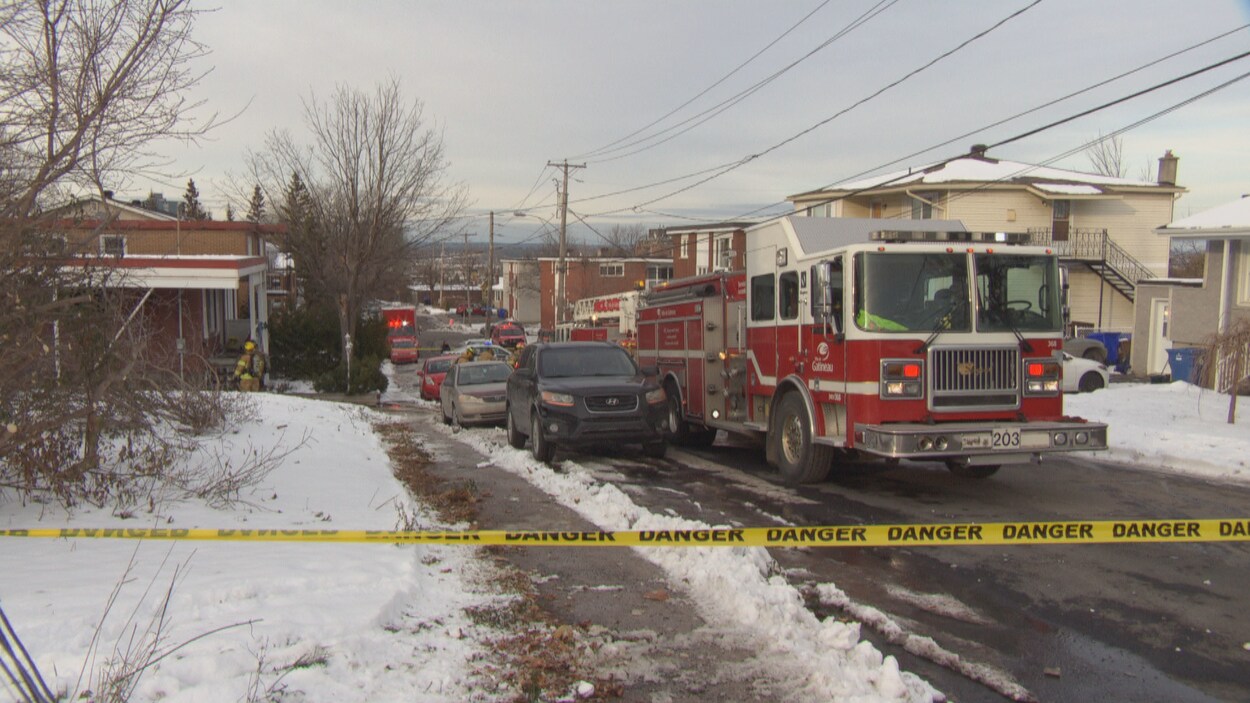 Un camion du Service de sécurité incendie de Gatineau stationné dans une rue près d'un cordon de sécurité en hiver.
