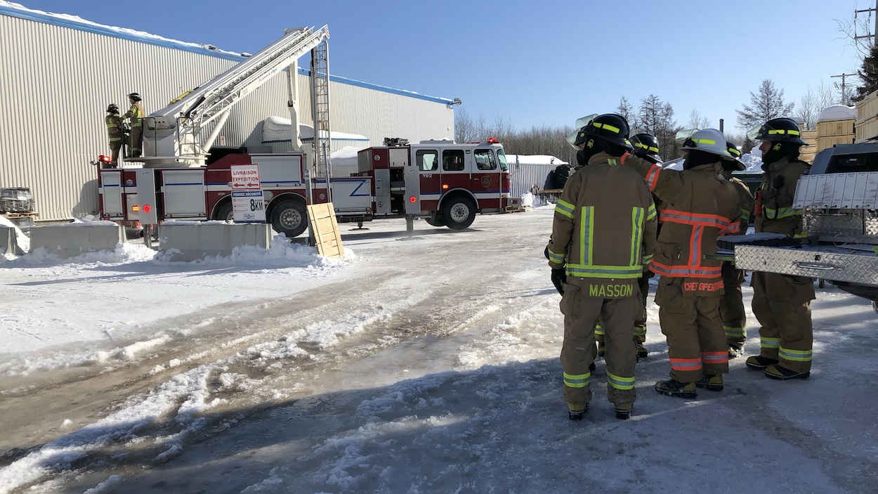 Des pompiers observent le site de l'incendie.