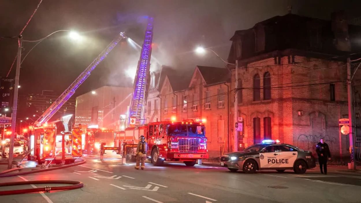 Des camions de pompiers près d'une rangée de maisons la nuit à Toronto