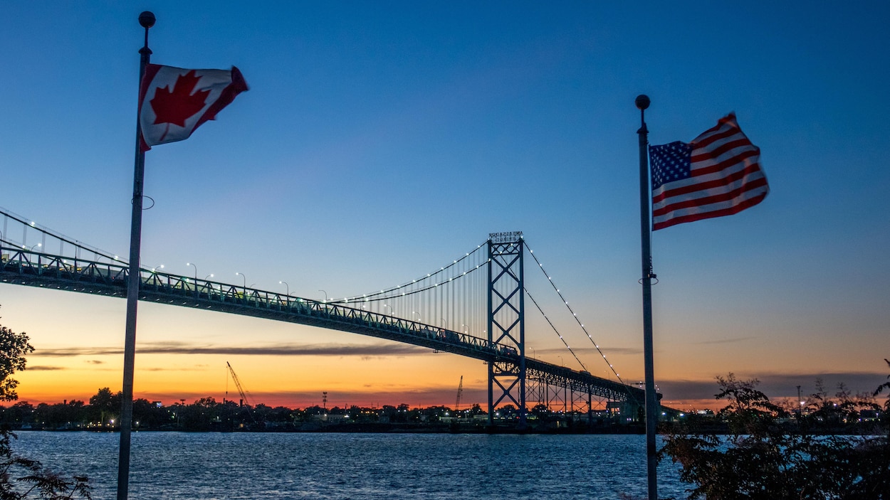 Une photo montre le pont Ambassadeur qui enjambe la rivière Détroit vu du côté de Windsor en Ontario avec les drapeaux canadien et américain.